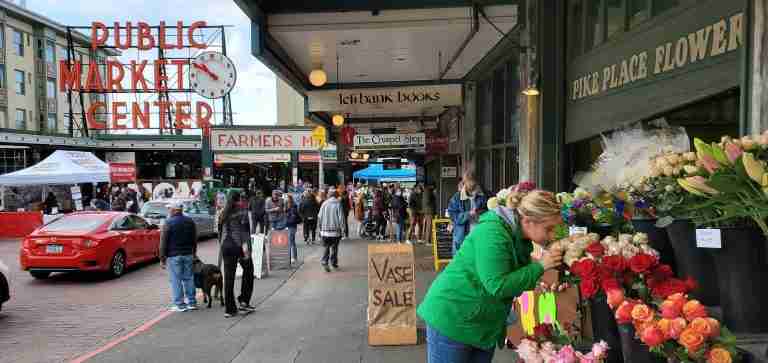 Seattle Goldendoodle Puppy Delivery Team stops to smell the flowers at the Pikes Place Market in Seattle
