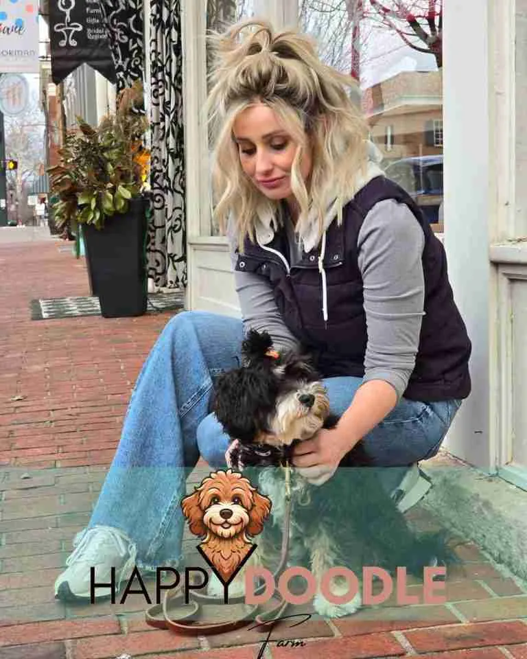 Felicia from Happy Doodle Farm taking a pre-trained Doodle puppy into public. Standing on a sidewalk.